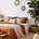 A cozy bedroom featuring natural decor elements, including a large bed with neutral bedding, wooden furniture, and lush green plants, creating a warm and inviting atmosphere.