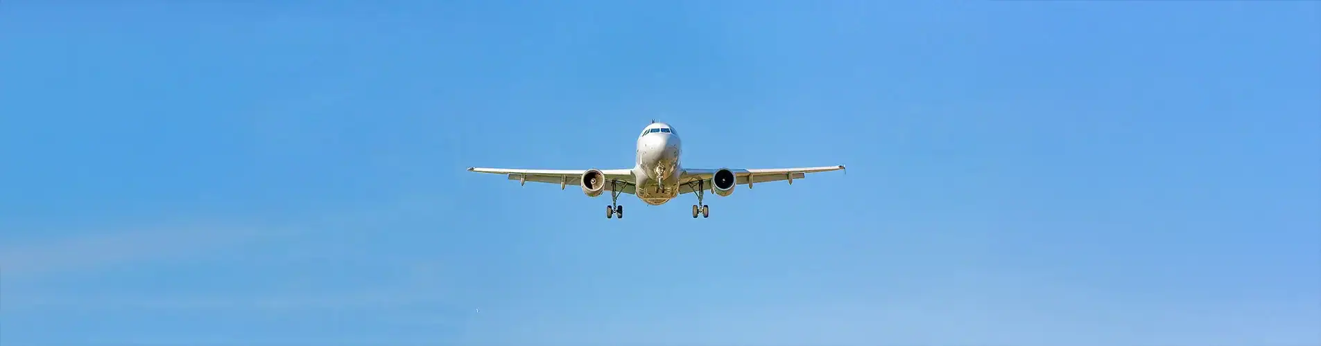 Cargo airplane in flight over clear blue sky, representing logistics and freight services.
