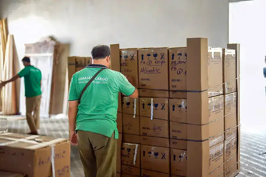 Des employés manipulent et inspectent de grands cartons dans l’entrepôt Limajari Cargo, garantissant des services logistiques sûrs et efficaces pour l’expédition internationale et la gestion du fret.