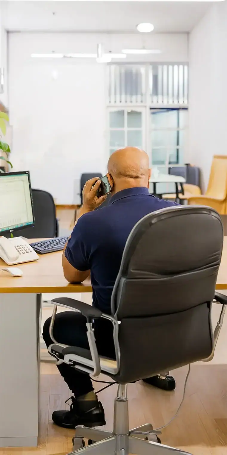 Employé de bureau de fret utilisant un téléphone fixe dans un environnement de bureau moderne.