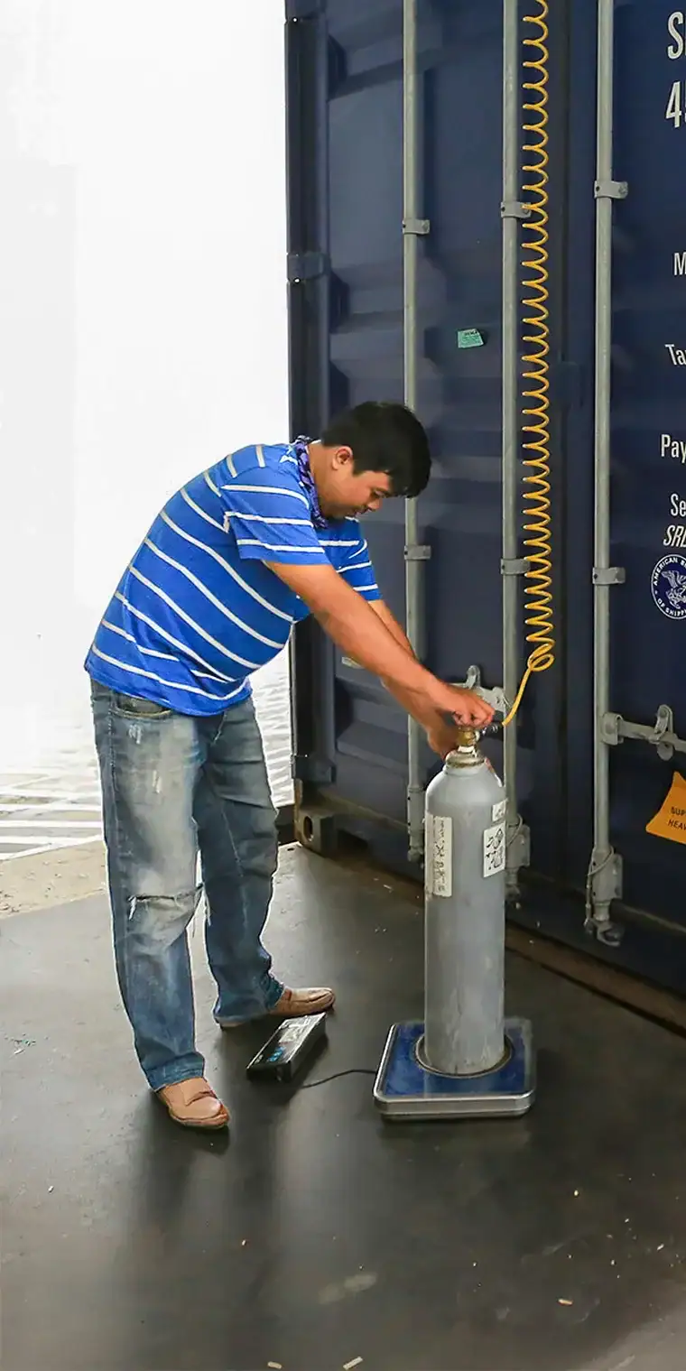 Manutention de fret aux installations de Limajari Cargo Employé sécurisant une bouteille de gaz chez Limajari Cargo, illustrant une manutention de fret efficace et des procédures de sécurité.