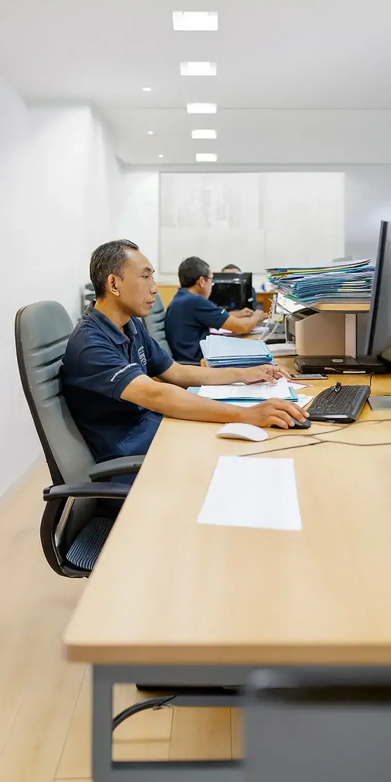 Équipe du bureau de fret dans les locaux de Limajari Cargo Membres de l'équipe de bureau travaillant à des bureaux avec des ordinateurs et de la paperasse dans un bureau de logistique de fret moderne et bien éclairé.