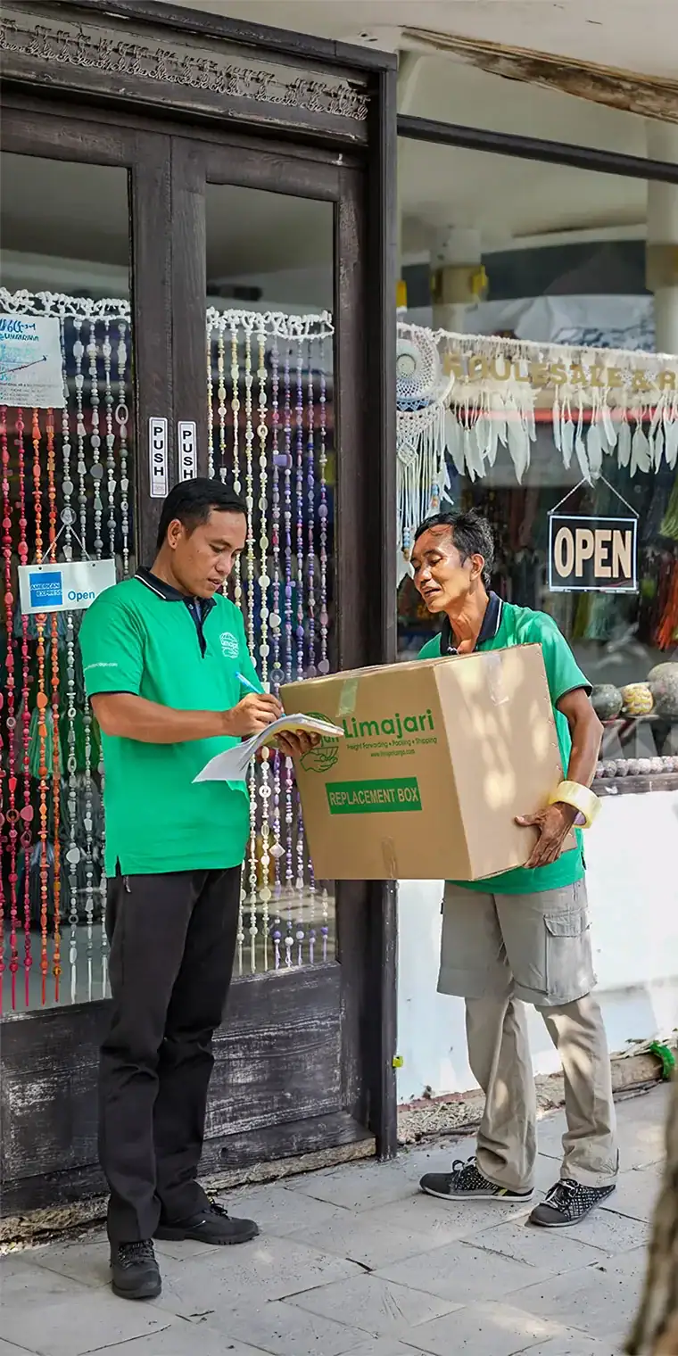 Two delivery personnel in green uniforms exchanging a package outside a store, showcasing reliable courier services by Limajari Cargo.