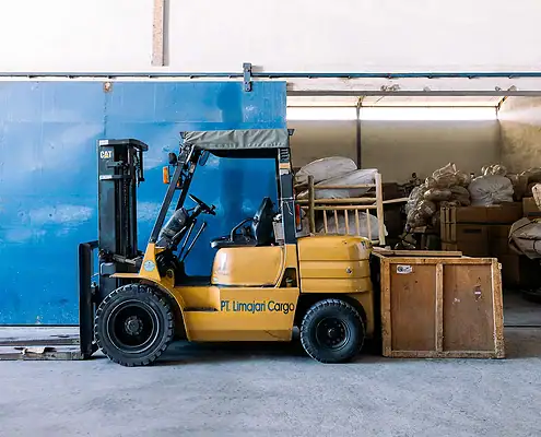 Un chariot élévateur de Limajari Cargo transportant des marchandises dans un entrepôt.
