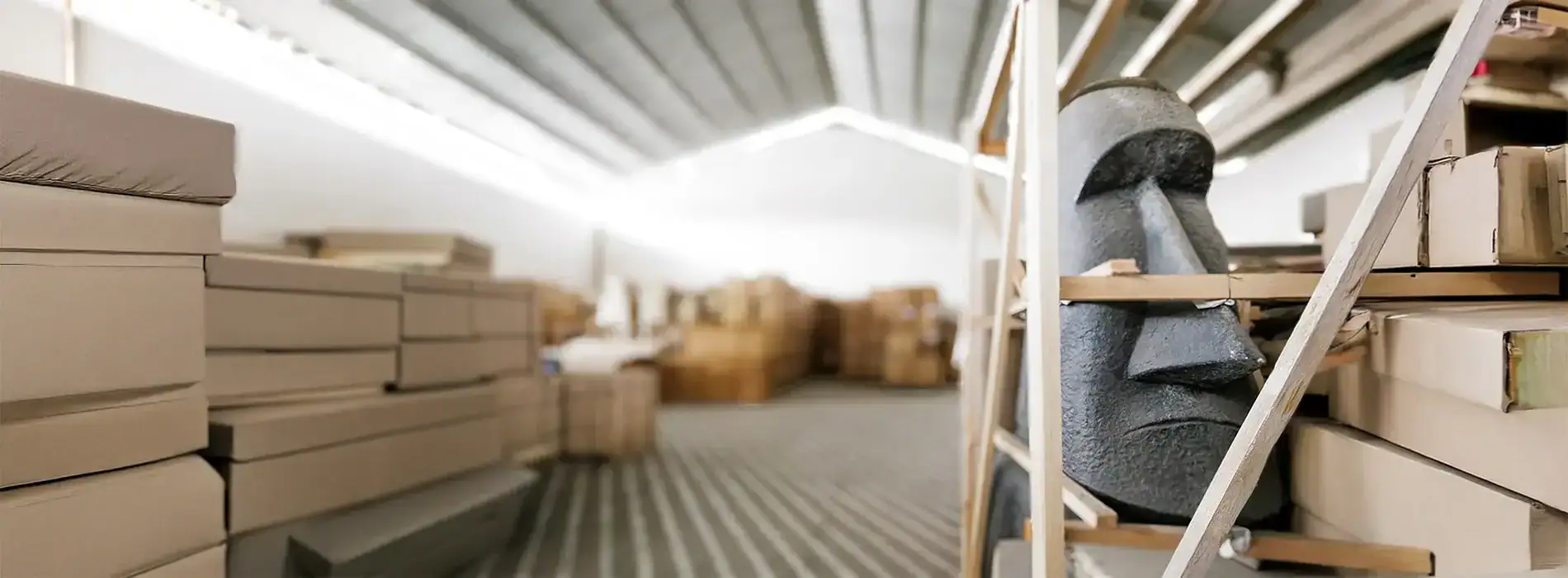 An image of a busy warehouse with neatly stacked boxes and a traditional Moai statue, highlighting efficient cargo handling and storage solutions.